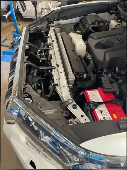 Open engine bay of a white vehicle with air-conditioning service gauges connected
