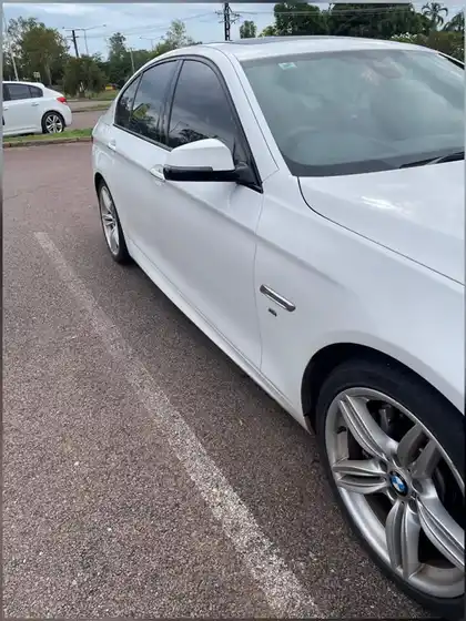 Side of a white BMW after cut and polish, the paint reflecting cleanly along the door and guard