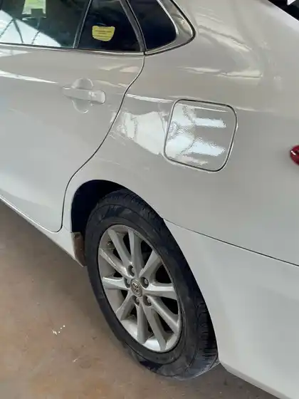 The same rear quarter panel on the white Camry, repaired and repainted with a clean wheel arch edge