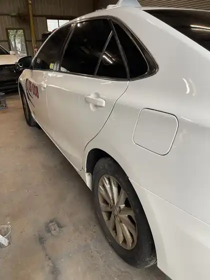 The same rear door and quarter panel on the white Camry, now smooth with an unbroken body line and matched white paint
