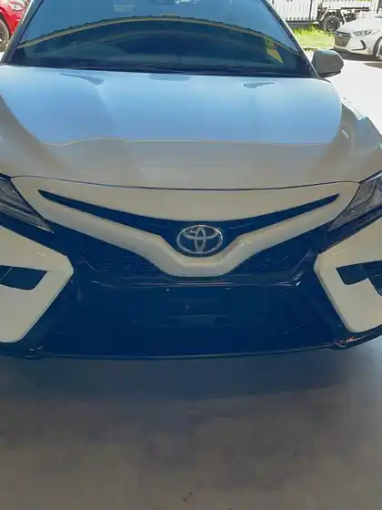 The same white Toyota Camry with a rebuilt front end, showing an aligned bonnet, new grille, bumper and headlights