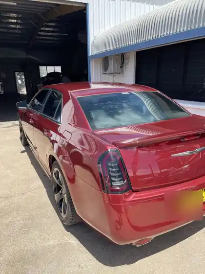 The same red Chrysler 300S outside after refinishing, the paint deep and even with sharp reflections along the body line