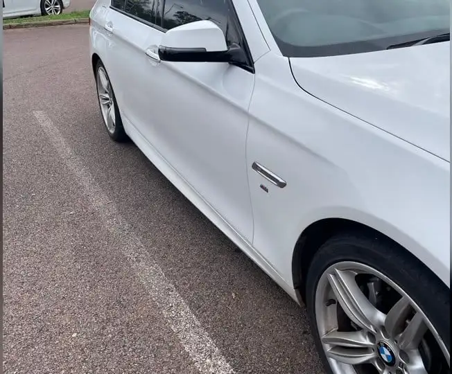 Sunlight reflecting across a polished white car as an example of the clear reflections owners look for after paint correction